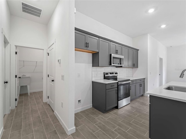 kitchen with stainless steel appliances, sink, dark hardwood / wood-style floors, and gray cabinetry