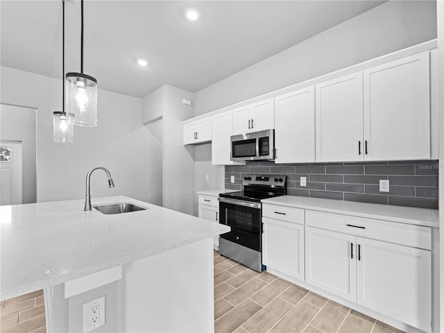 kitchen featuring a center island with sink, stainless steel appliances, white cabinetry, pendant lighting, and sink