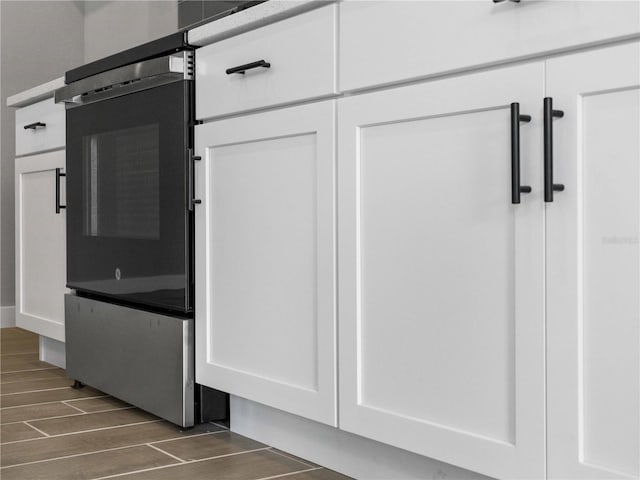 interior details with dark wood-type flooring, white cabinetry, and wall oven