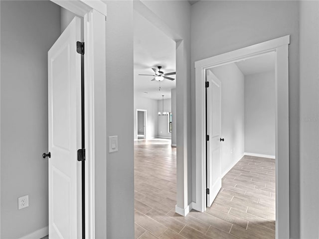 corridor with an inviting chandelier and light hardwood / wood-style floors