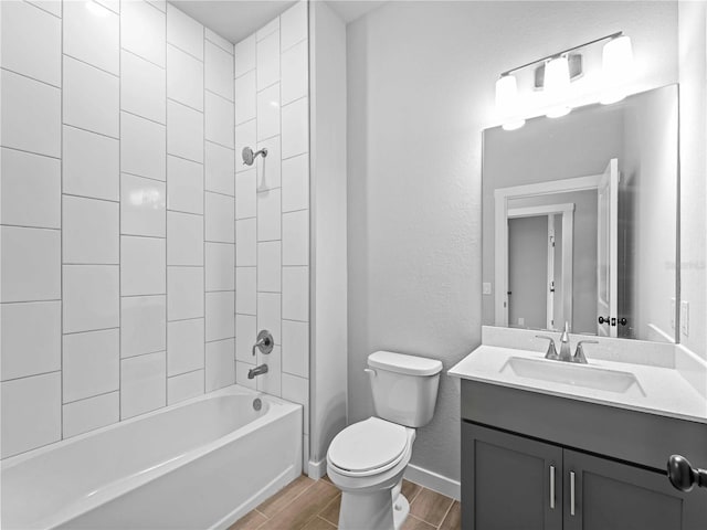 full bathroom with hardwood / wood-style floors, tiled shower / bath, toilet, and vanity