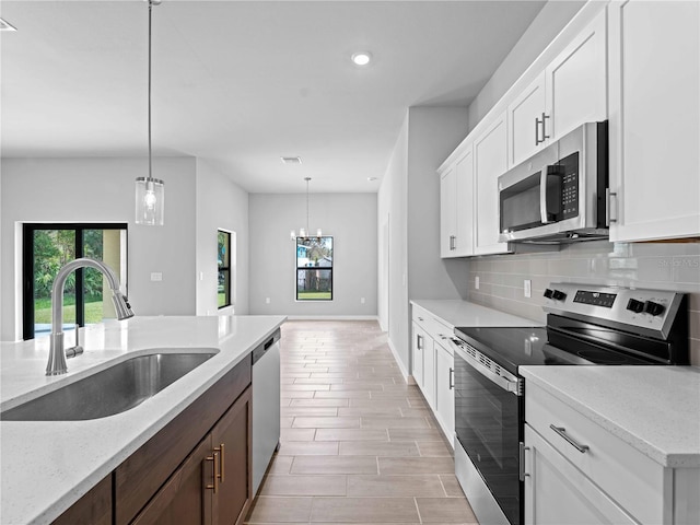 kitchen with white cabinets, stainless steel appliances, sink, and light stone countertops