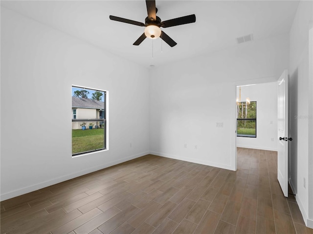 empty room featuring wood-type flooring and ceiling fan with notable chandelier