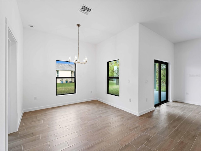 unfurnished room with a chandelier, plenty of natural light, and light wood-type flooring