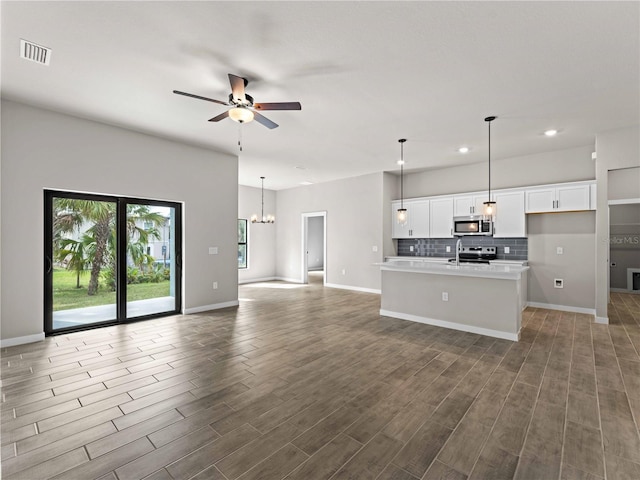 kitchen with dark hardwood / wood-style flooring, hanging light fixtures, a kitchen island with sink, and white cabinets