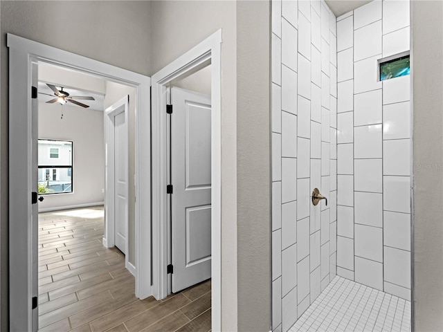 bathroom with tiled shower, ceiling fan, and wood-type flooring