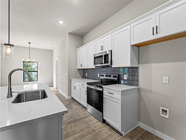 kitchen with stainless steel appliances, sink, light stone counters, hanging light fixtures, and white cabinets