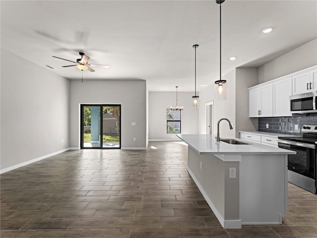 kitchen with a center island with sink, sink, white cabinetry, appliances with stainless steel finishes, and decorative light fixtures