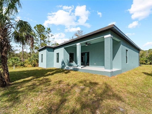 back of house with a lawn and ceiling fan