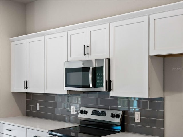 kitchen with backsplash, white cabinets, and stainless steel appliances