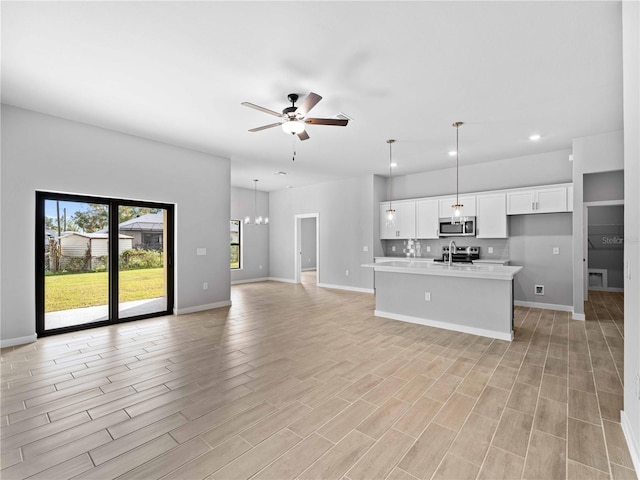 unfurnished living room with ceiling fan with notable chandelier and light wood-type flooring