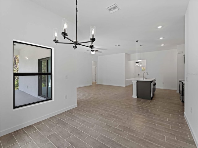 unfurnished living room with ceiling fan with notable chandelier, sink, and light wood-type flooring