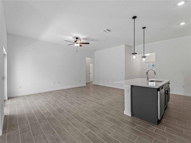 kitchen featuring a center island with sink, hanging light fixtures, dark wood-type flooring, and sink