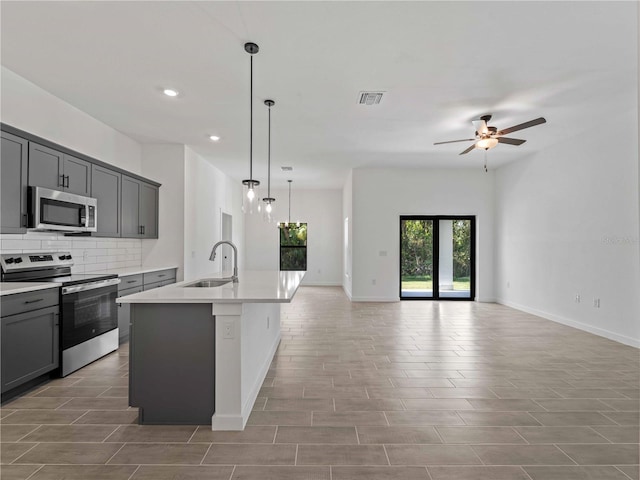 kitchen featuring gray cabinets, sink, a kitchen island with sink, and stainless steel appliances