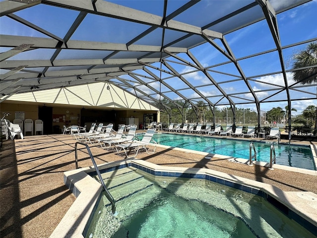 view of pool featuring a hot tub, a patio area, and glass enclosure