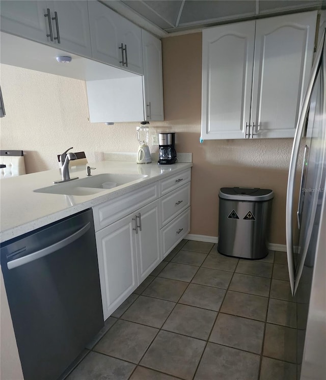 kitchen with white cabinetry, stainless steel appliances, light tile flooring, light stone counters, and sink