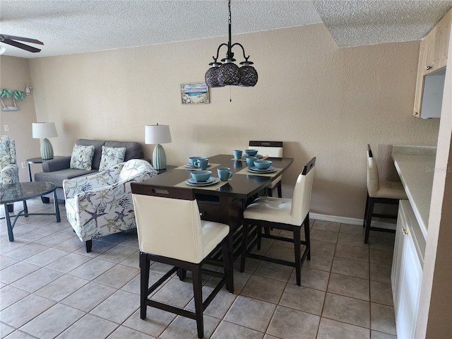 dining room with ceiling fan with notable chandelier, light tile floors, and a textured ceiling