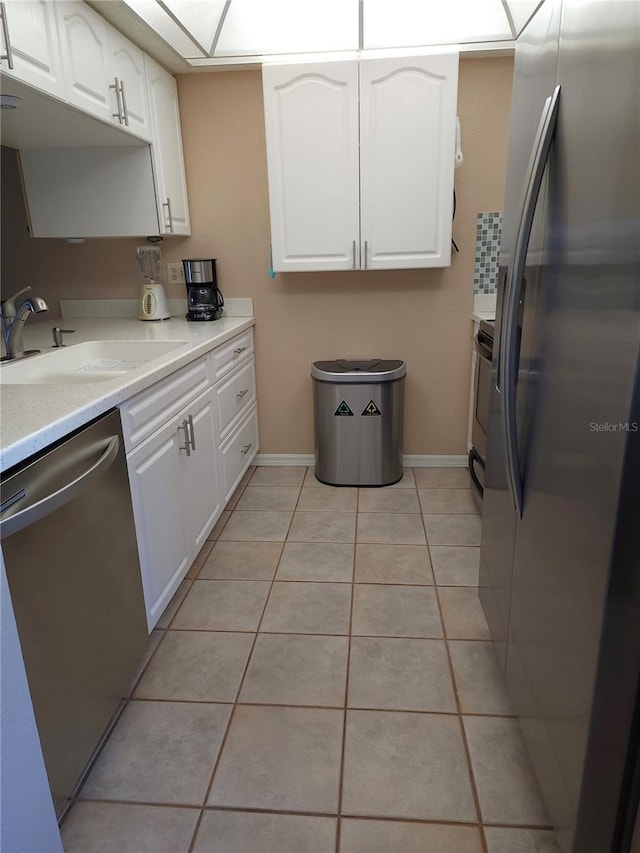 kitchen featuring sink, white cabinetry, stainless steel appliances, and light tile floors