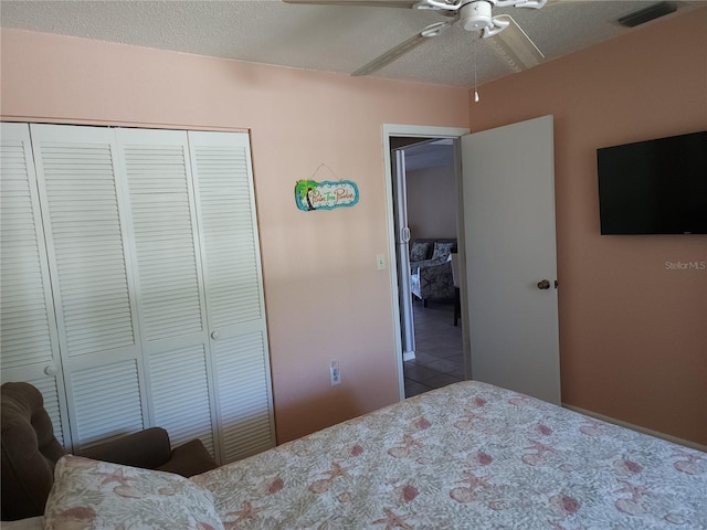 bedroom featuring ceiling fan, tile flooring, a closet, and a textured ceiling