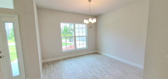 spare room featuring light wood-type flooring and a notable chandelier