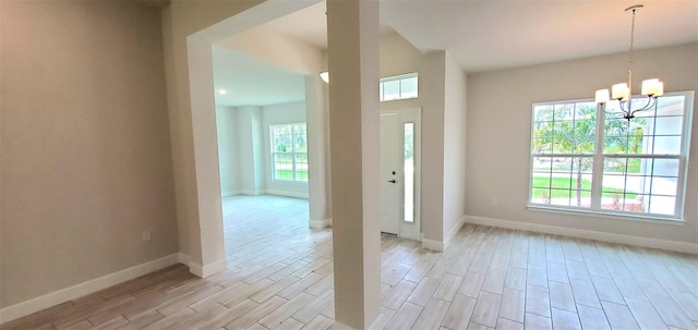 foyer featuring a notable chandelier, light hardwood / wood-style floors, and a healthy amount of sunlight