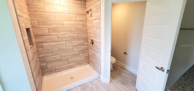 bathroom featuring hardwood / wood-style floors, toilet, and tiled shower