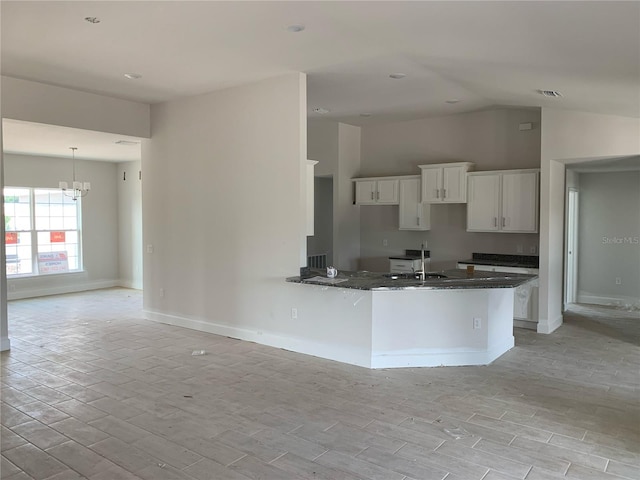 kitchen featuring a notable chandelier, sink, white cabinetry, light wood-type flooring, and dark stone countertops