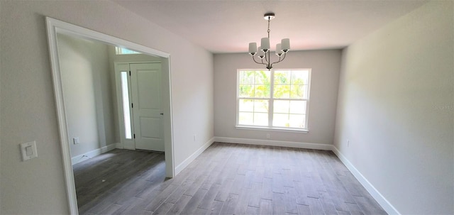 unfurnished room featuring wood-type flooring and a notable chandelier