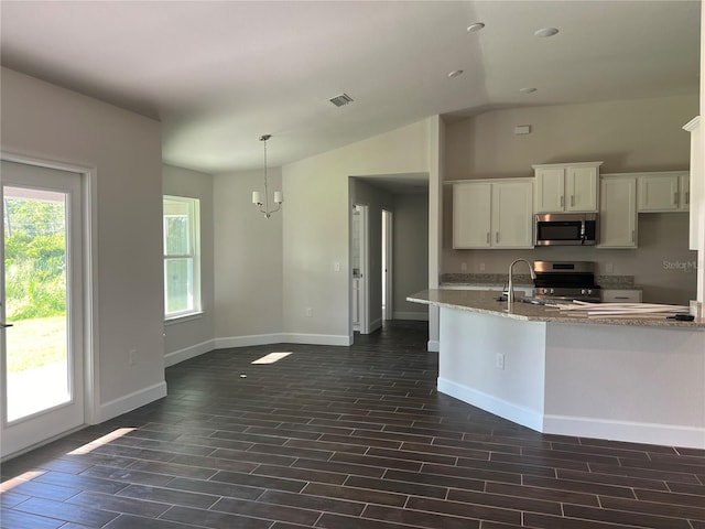 kitchen with appliances with stainless steel finishes, white cabinetry, dark wood-type flooring, and light stone counters