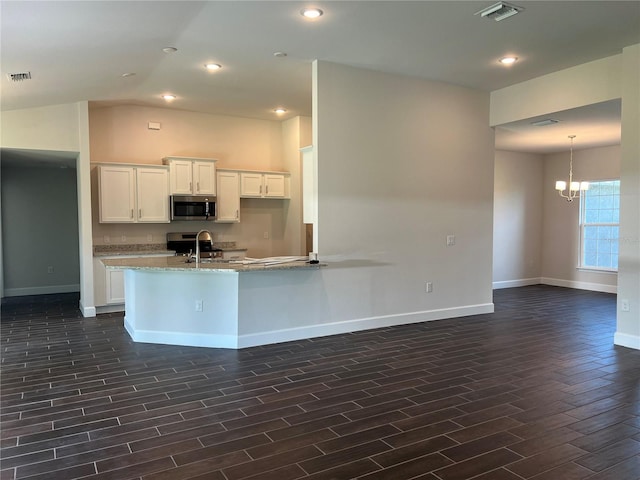 kitchen with white cabinetry, light stone countertops, dark hardwood / wood-style flooring, stainless steel appliances, and a chandelier