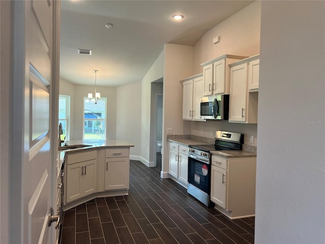 kitchen with appliances with stainless steel finishes, white cabinetry, light stone counters, sink, and a notable chandelier