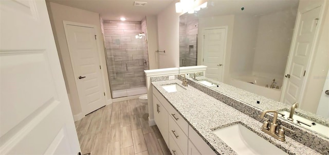 bathroom featuring toilet, hardwood / wood-style flooring, vanity, and walk in shower