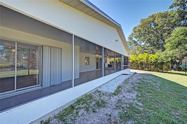 view of property exterior with a sunroom and a lawn