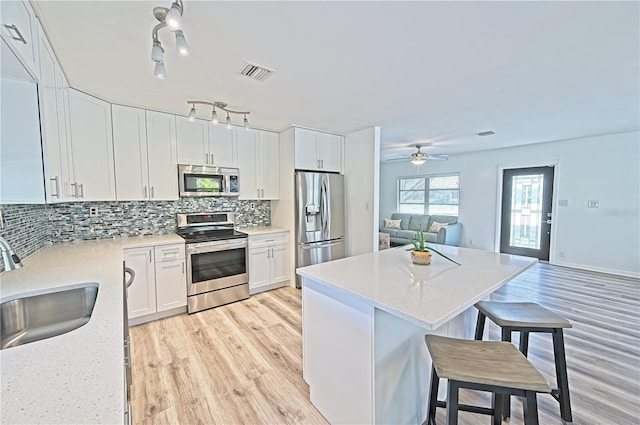 kitchen with ceiling fan, white cabinets, appliances with stainless steel finishes, light hardwood / wood-style floors, and rail lighting