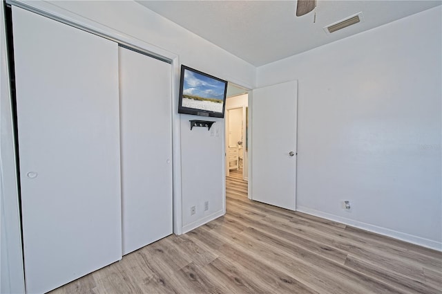 unfurnished bedroom featuring ceiling fan, light hardwood / wood-style flooring, and a closet