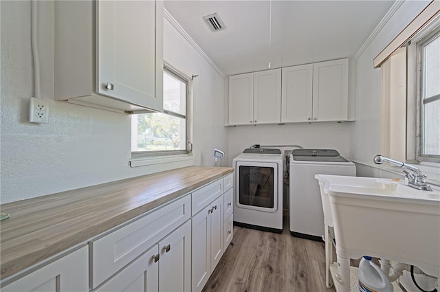 laundry area with separate washer and dryer, cabinets, light hardwood / wood-style floors, sink, and crown molding