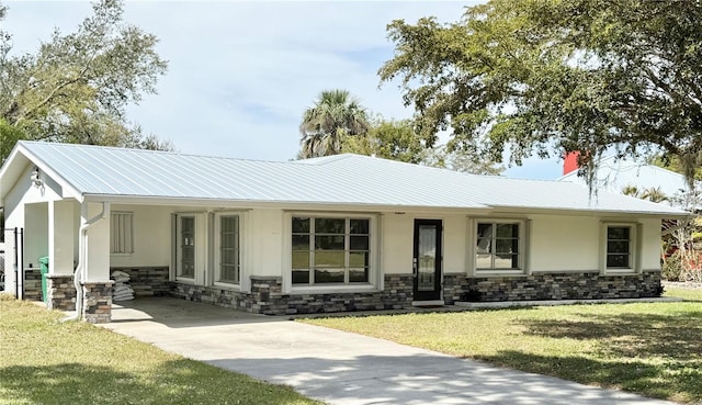 single story home with stone siding, metal roof, a front lawn, and stucco siding