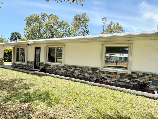 exterior space featuring a front yard, stone siding, and stucco siding