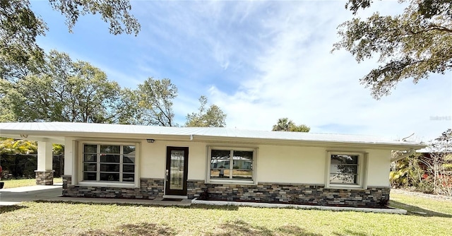 ranch-style home featuring stone siding, a front yard, and stucco siding