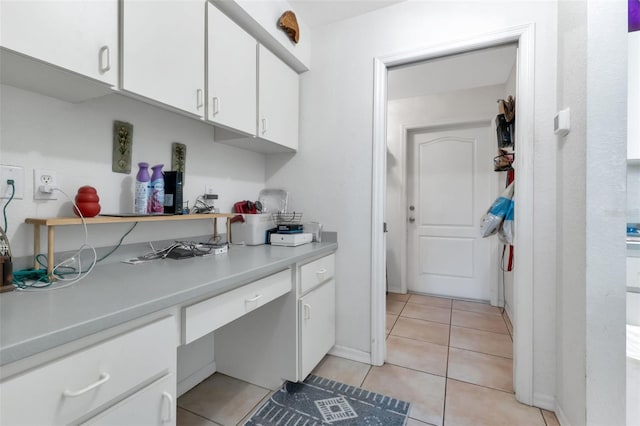 kitchen with white cabinetry, light tile patterned floors, and built in desk