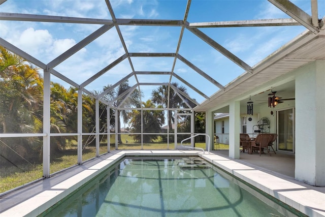 view of swimming pool featuring glass enclosure, ceiling fan, and a patio