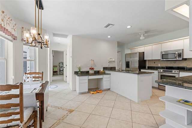 kitchen with hanging light fixtures, tasteful backsplash, stainless steel appliances, ceiling fan with notable chandelier, and white cabinetry