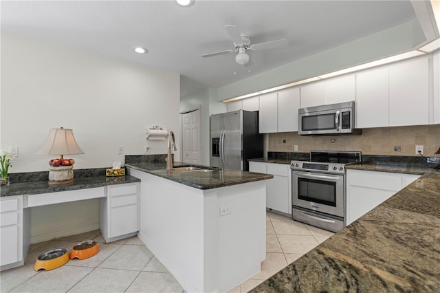 kitchen with ceiling fan, appliances with stainless steel finishes, white cabinetry, backsplash, and dark stone countertops