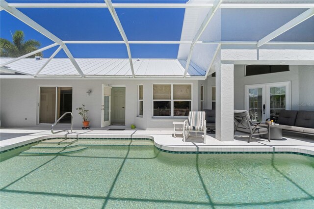 view of swimming pool with french doors, a lanai, an outdoor living space, and a patio