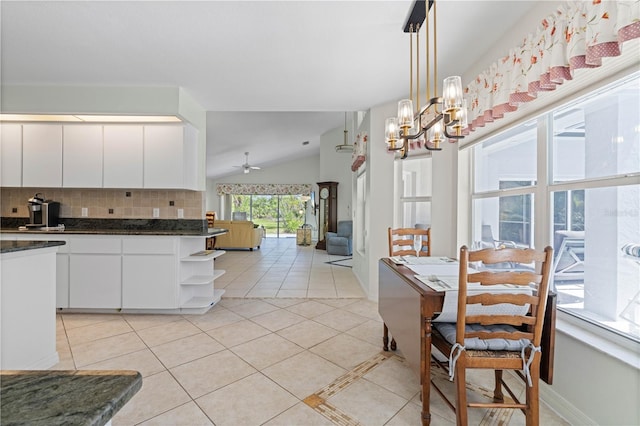 kitchen featuring backsplash, vaulted ceiling, white cabinetry, and ceiling fan with notable chandelier