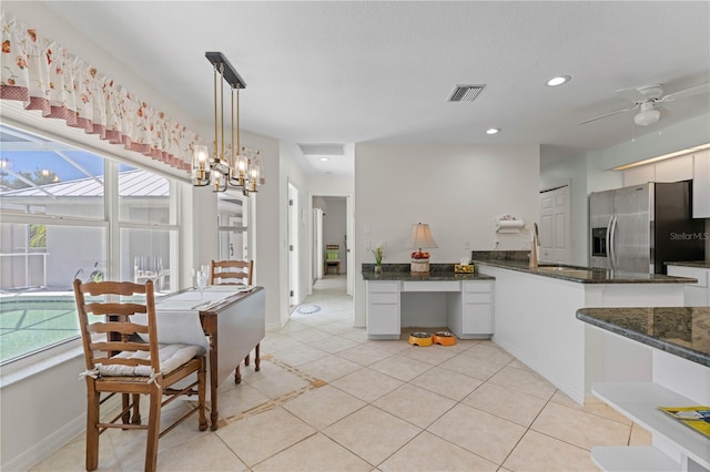 kitchen with a healthy amount of sunlight, pendant lighting, ceiling fan with notable chandelier, and stainless steel refrigerator with ice dispenser