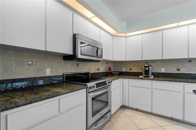 kitchen featuring stainless steel appliances, backsplash, dark stone counters, and white cabinets