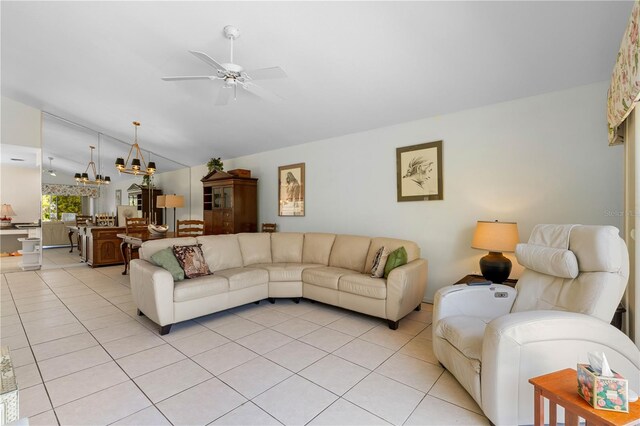 living room featuring light tile flooring, vaulted ceiling, and ceiling fan with notable chandelier