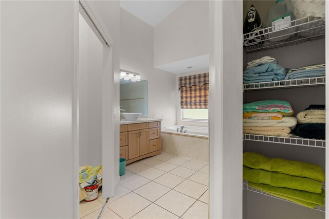 bathroom featuring tile flooring, vanity, and a bath to relax in