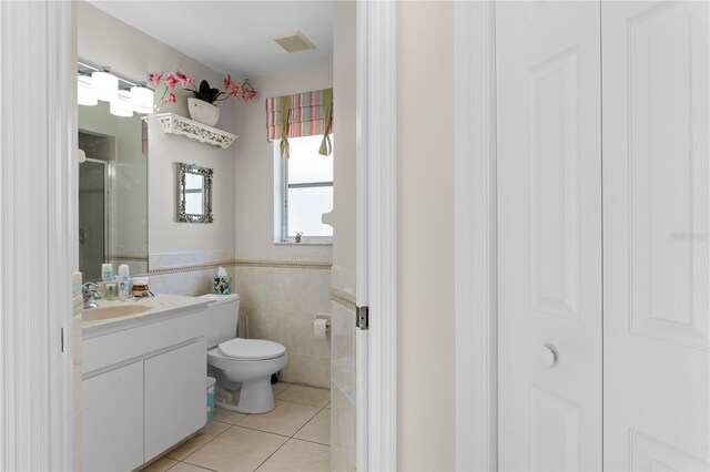 bathroom featuring tile flooring, tile walls, toilet, and oversized vanity